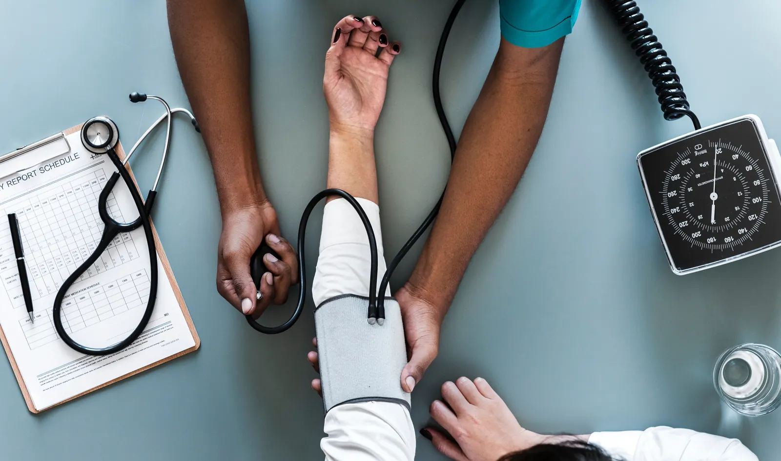 Una profesional de salud mide la presión arterial en el brazo de una paciente